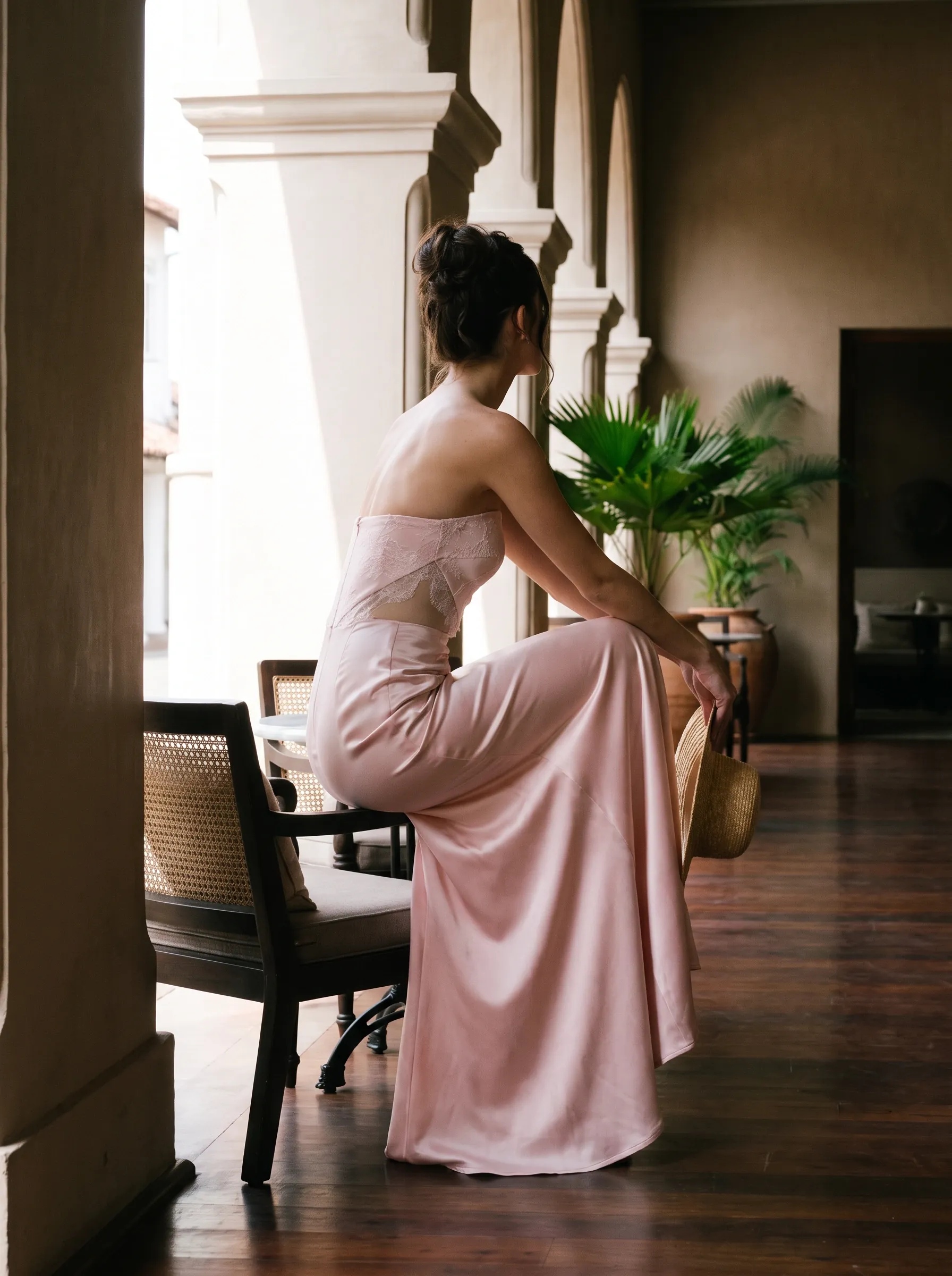a SHER cocktail dress in pale pink satin, a maxi, on a colonial verandah